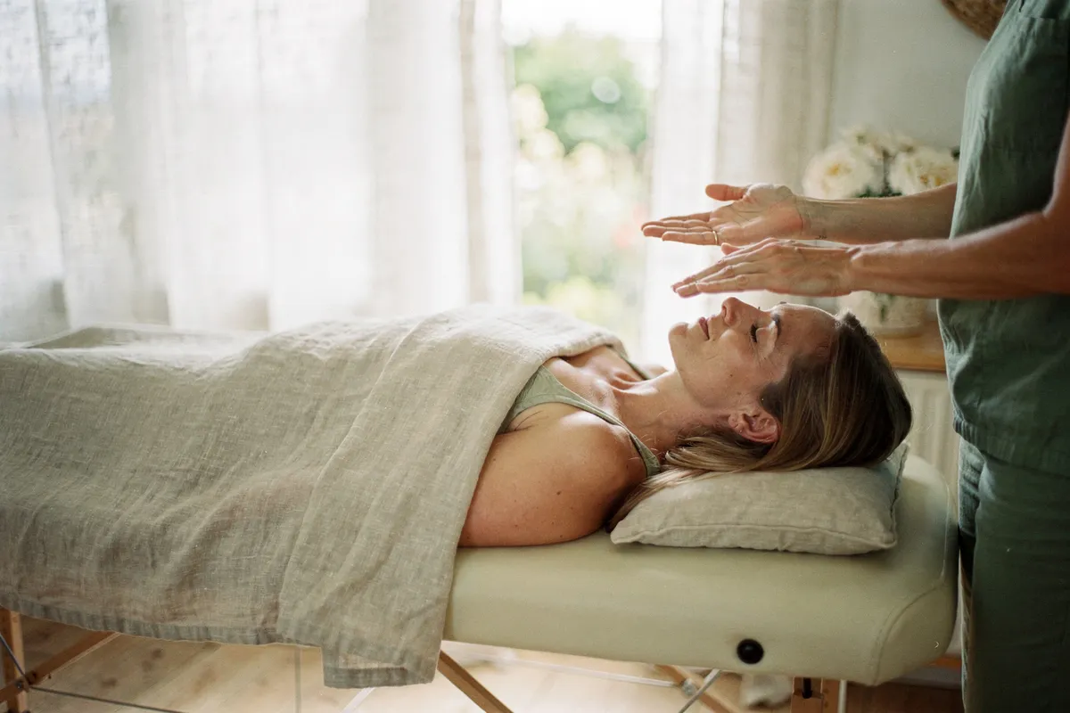 Une femme détendue, allongée les yeux fermés, lors d'une séance de Reiki.